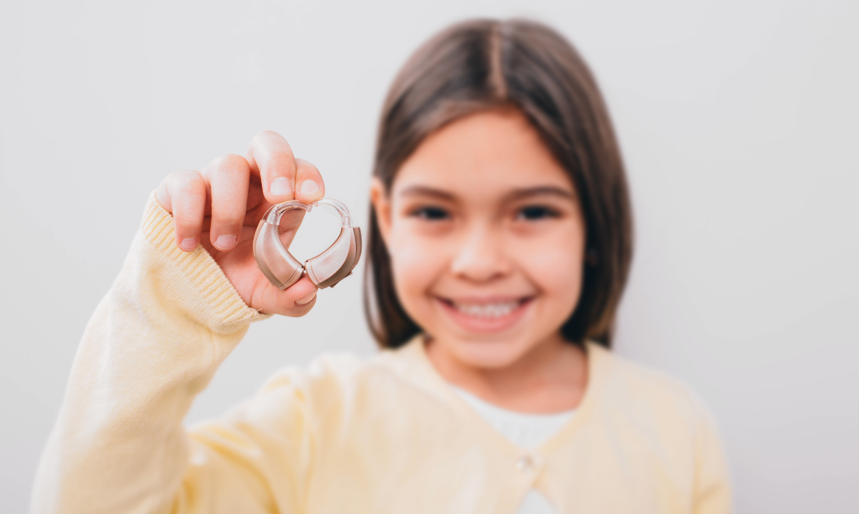 Girl holding up her hearing aid