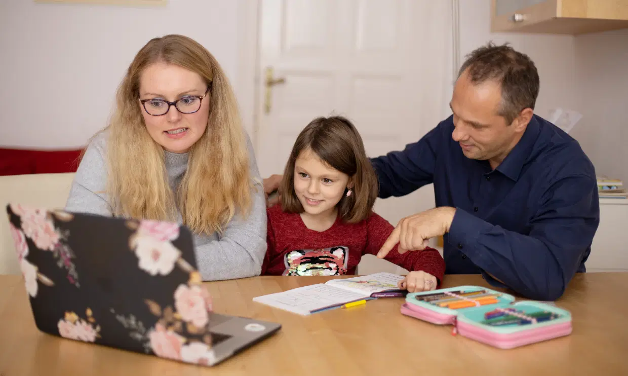Two parents and child looking at laptop