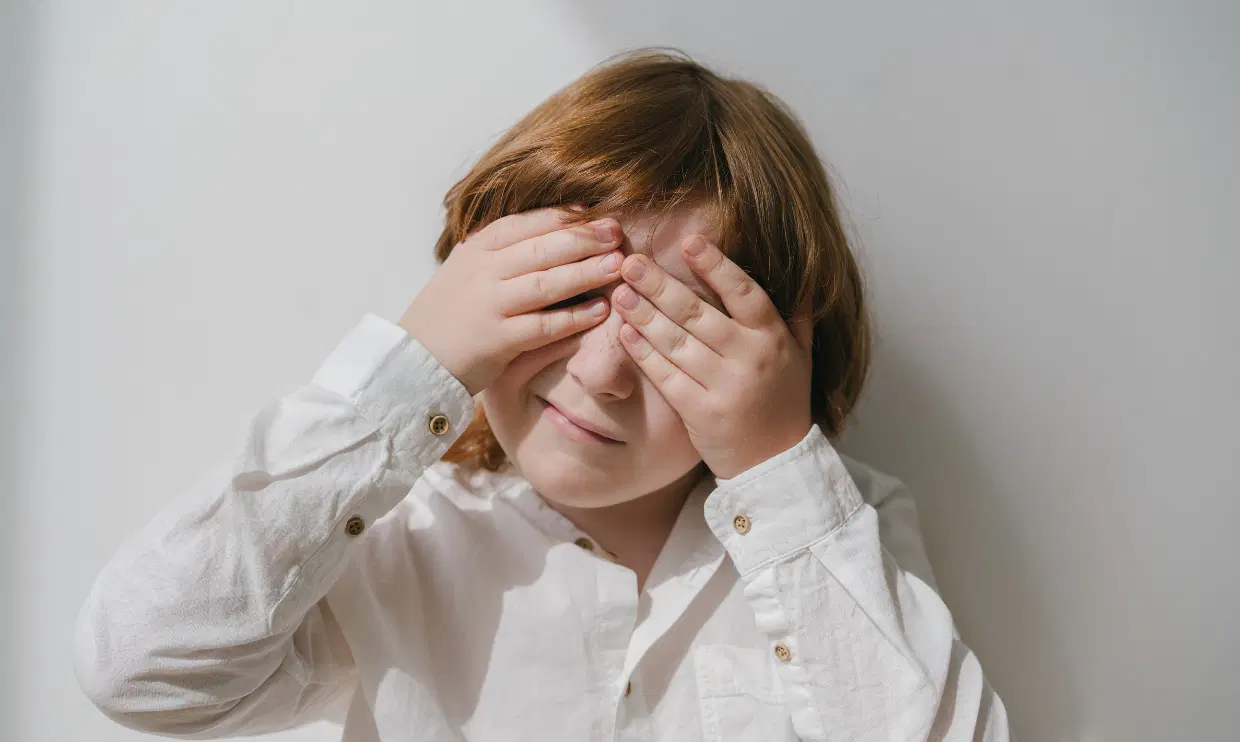 Child covering face with hands