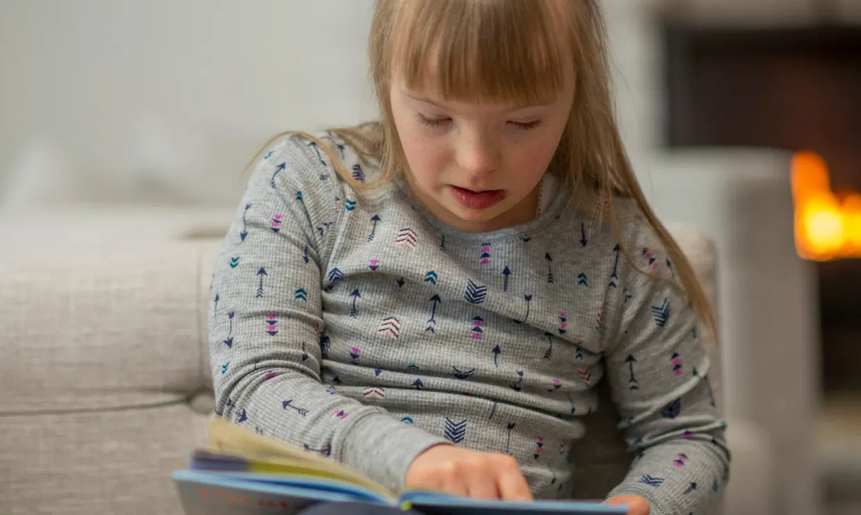 Child with Down syndrome reading a book
