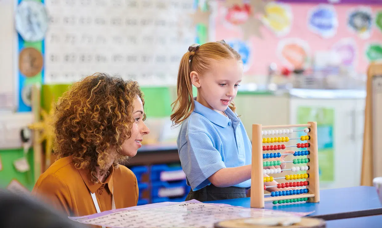 Teacher watching a child count using a manipulative
