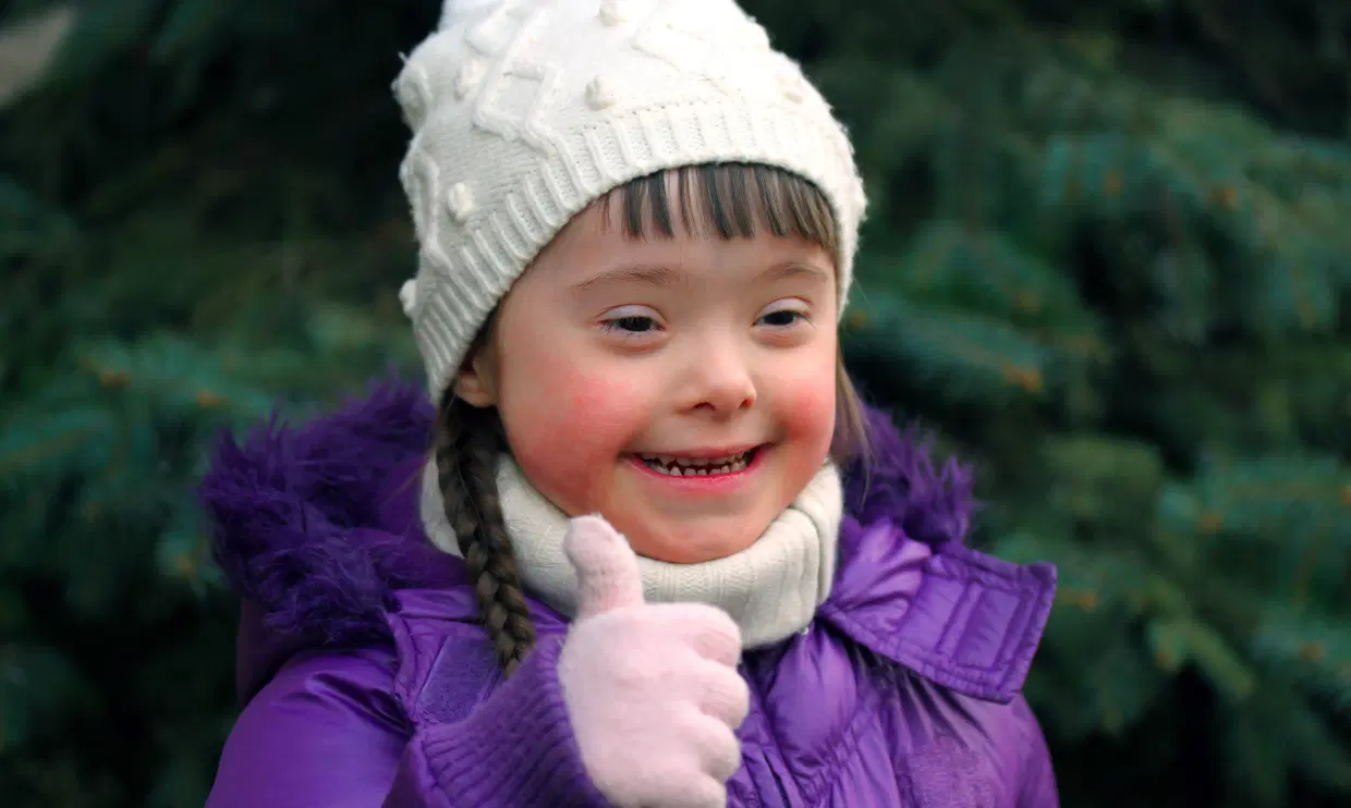 Child dressed in warm clothes giving thumbs up
