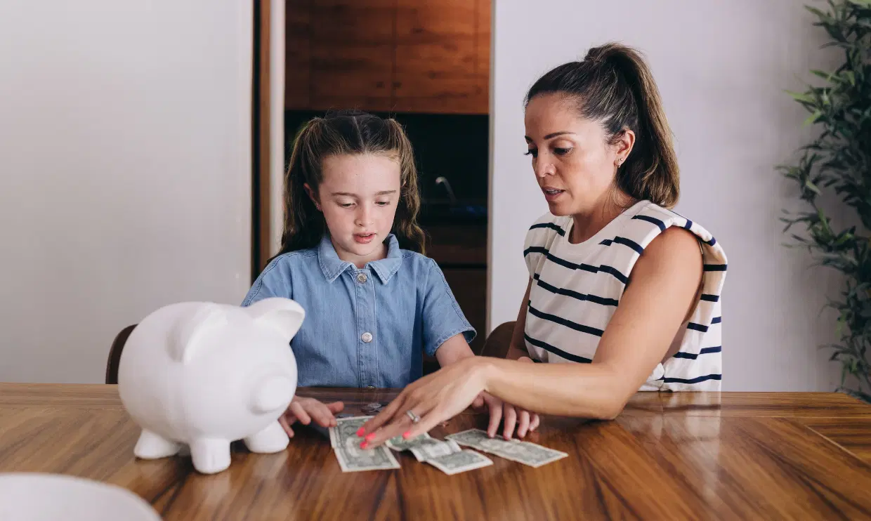 Parent and child counting money from a piggy bank