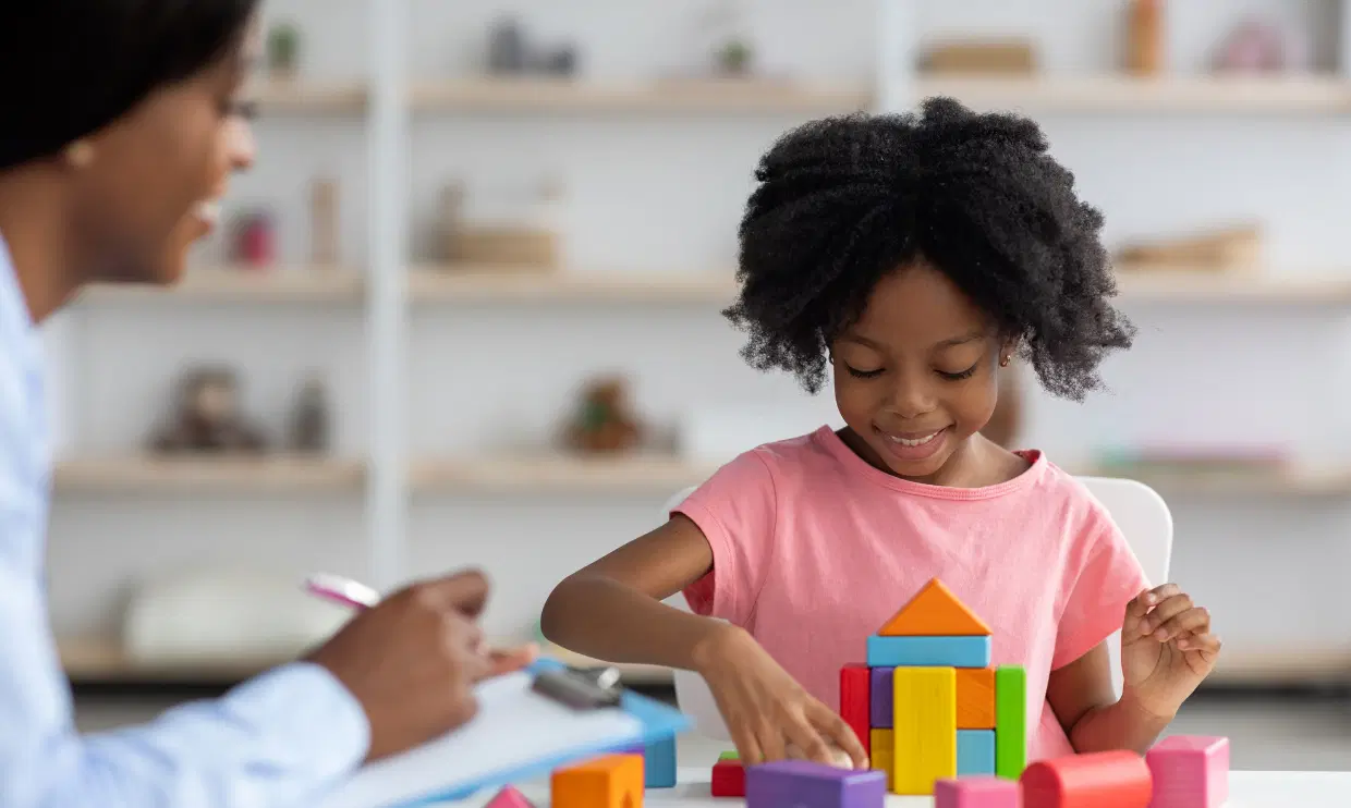 Child manipulating blocks while adult observes